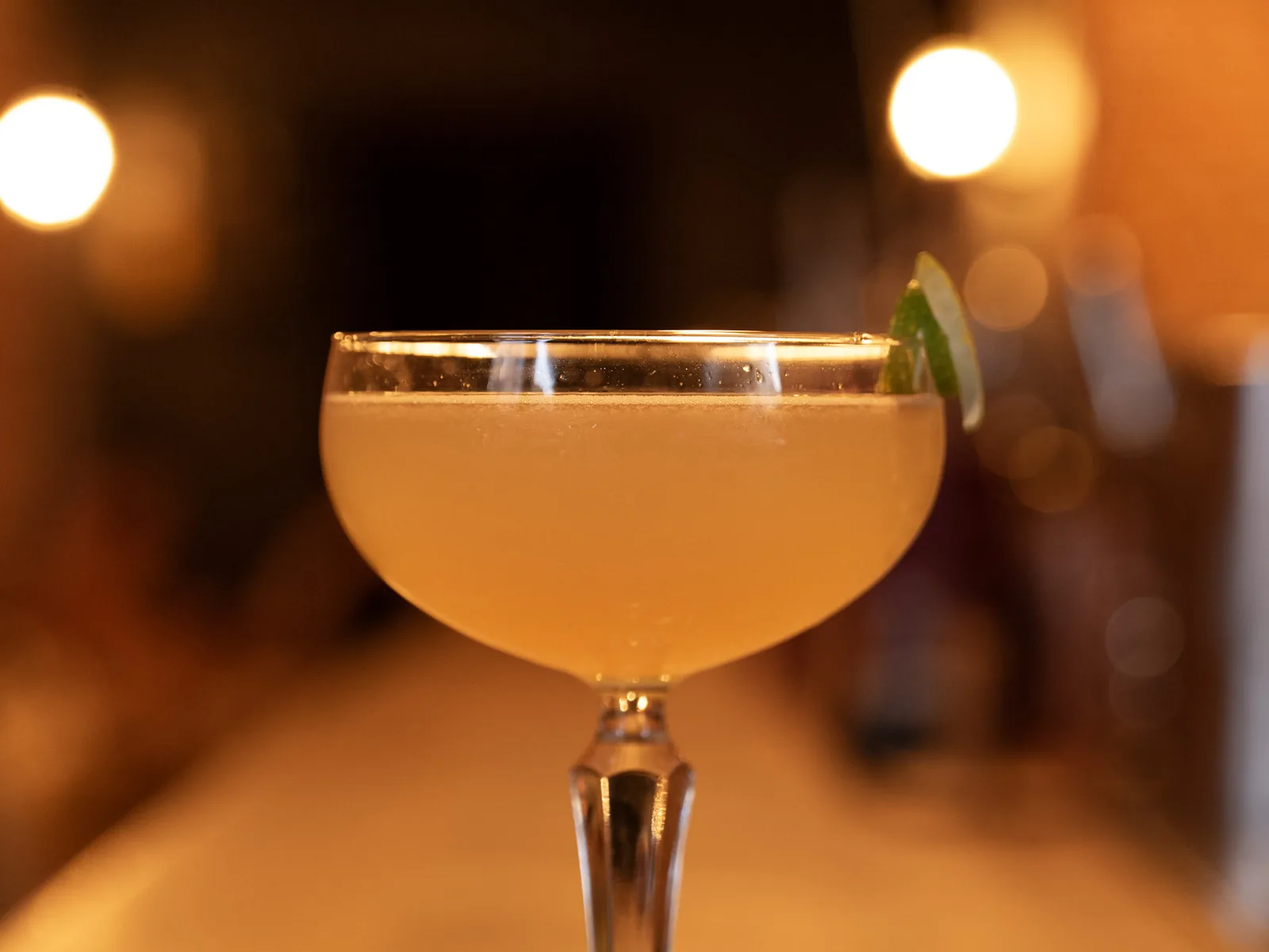 A classic Daiquiri in a chilled coupe with a lime wheel, on the bar at The Modern Alchemist, a rum bar in Brussels